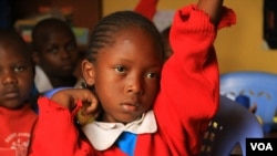 FILE - A student raises her hand to ask a question during class at the Kibera School for Girls in Nairobi, Kenya.