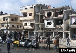 Syrian citizens gather at the scene where two blasts exploded in the pro-government neighborhood of Zahraa, in Homs province, Syria, Feb. 21, 2016. The Islamic State group claimed responsibility for this and another attack Sunday.