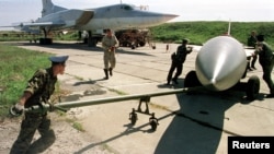 Ground stuff tow a cruise missile towards Tupolev-22 "Backfire" plane for loading at a military base near the city of Ussuriysk in this September 17, 1999 file photo. 