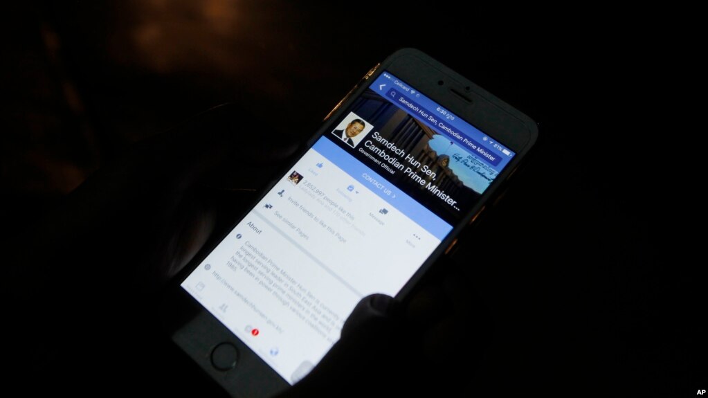 In this March 1, 2016 photo, a man views Cambodian Prime Minister Hun Sen's Facebook page on his mobile phone at a sidewalk in downtown Phnom Penh, Cambodia. Cambodiaâ€™s long-ruling Hun Sen and exiled opposition leader Sam Rainsy have gotten an early start