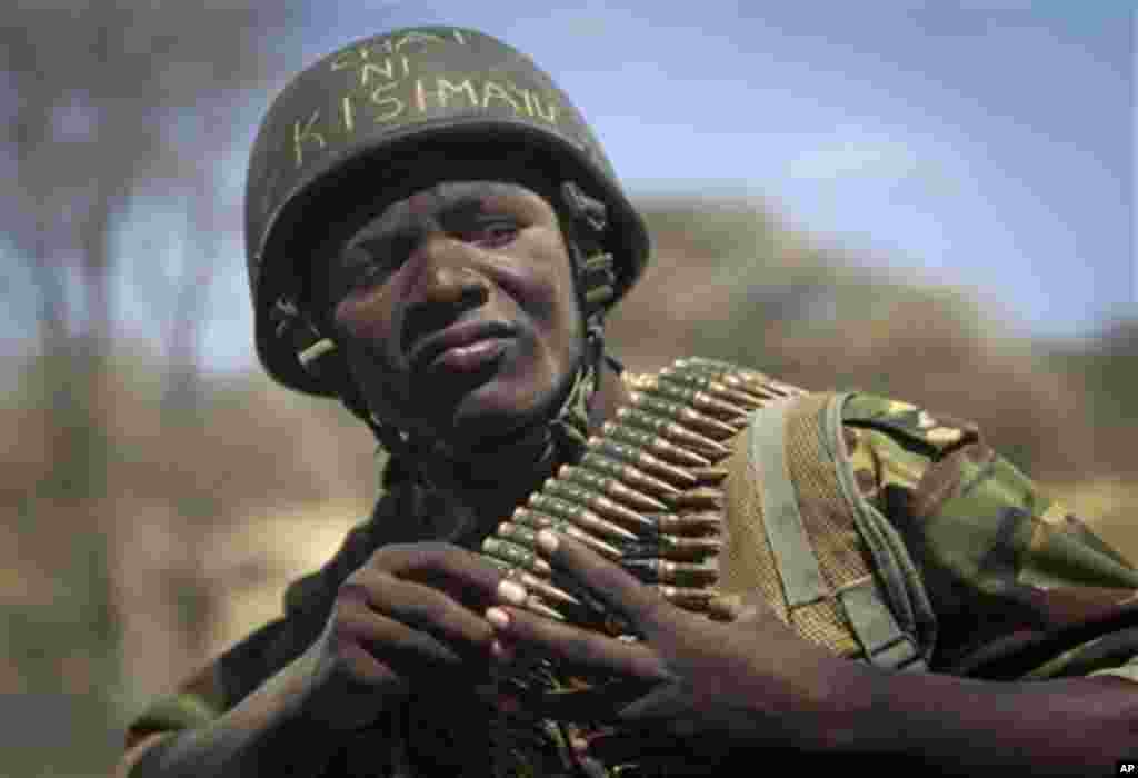 Kenyan army soldier Nicholas Munyanya, wearing a helmet on which is written in Kiswahili "Tea in Kismayo", referring to a key strategic Somali town under the control of al-Shabab, checks his ammunition belt near the town of Dhobley, currently under contro