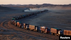 Thousands of heavy-duty trucks loaded with coal are lined up for up to 130 kilometers from the Mongolia-China border on a sole road in the Gobi desert, Mongolia, Oct. 29, 2017. The journey can take more than a week.