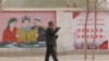 FILE - A farmer walks past government propaganda depicting ethnic minority residents reading the constitution with a slogan that reads, "Unity, Stability is fortune, Separatism and Turmoil is misfortune," near Kashgar in Xinjiang, northwestern China, on March 19, 2021.