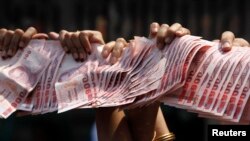 Anti-government protesters hold Thai baht banknotes to donate to protest leader Suthep Thaugsuban (unseen) as he leads a march through central Bangkok, March 28, 2014. 