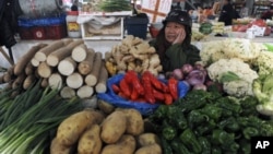 A vendor waits for customers at his vegetable stall at a market in Hangzhou, Zhejiang province, January 12, 2012. China's inflation rate eased to a 15-month low in December, though food prices are a reminder of the risks the government is weighing as it t