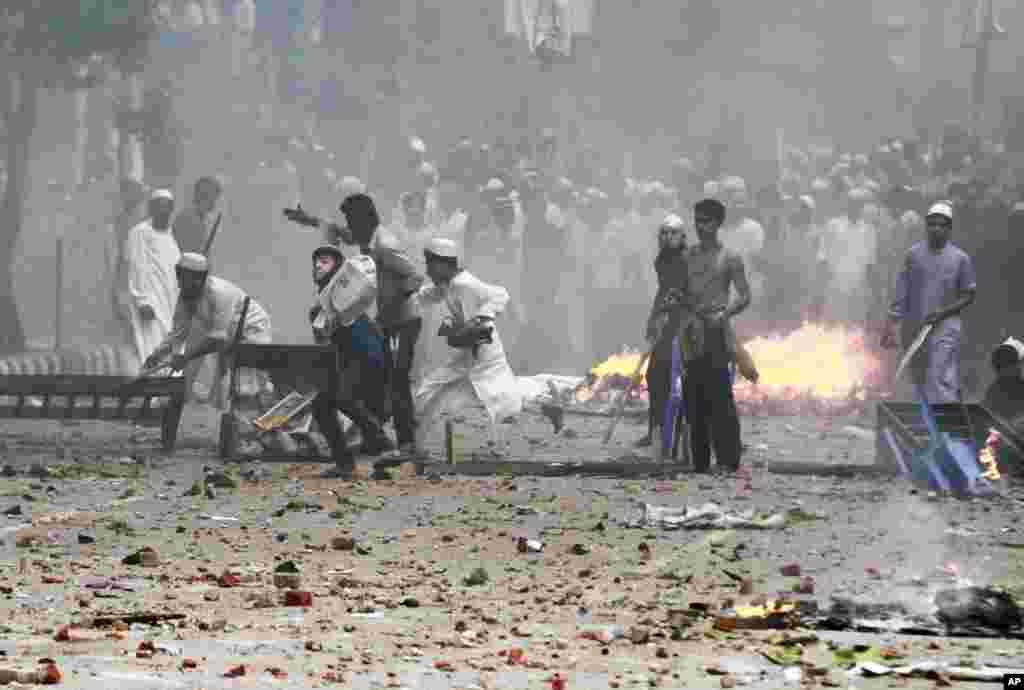Bangladeshi protesters throw stones at policemen during a protest in Dhaka, Bangladesh, to demand that the government enact an anti-blasphemy law.