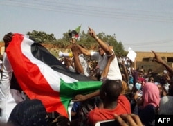 FILE - Sudanese protesters wave their national flag and chant slogans during an anti-government demonstration in the capital Khartoum's twin city of Omdurman on Jan. 31, 2019.