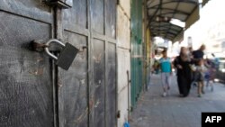 Across the entire Israeli-occupied Palestinian West Bank, businesses and shops closed as a sign of support for Palestinian prisoners on hunger strike being held in Israeli jails. Pedestrians walk by locked shops in Ramallah, June 8, 2014. 