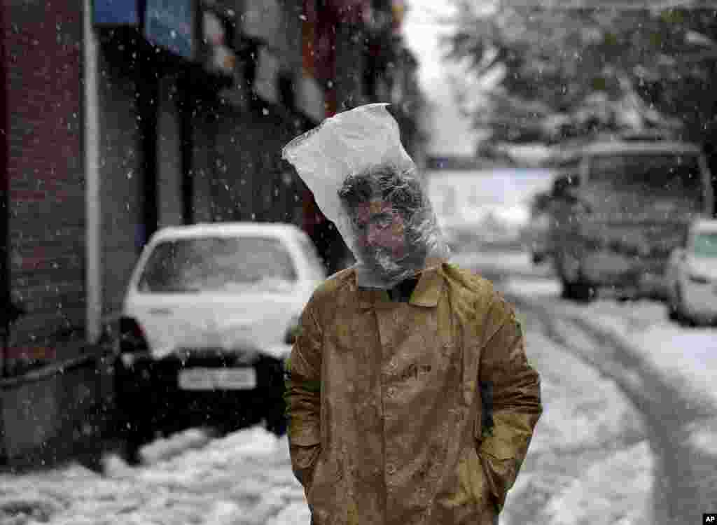 A man covers his head with a plastic bag as it snows in Srinagar, India-controlled Kashmir.