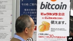 FILE - A man walks past a poster of bitcoin displayed at a retail store in Tokyo, Jan. 19, 2018.