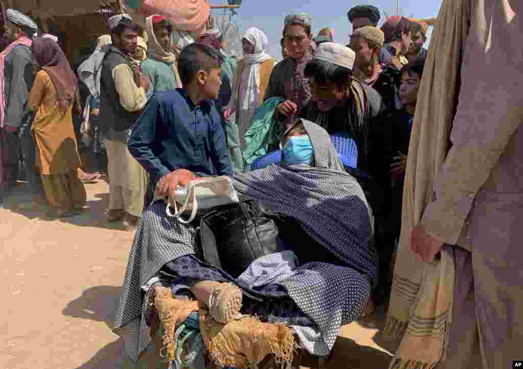 A porter pushes a wheelbarrow carrying an elderly Afghan woman as they enter into Pakistan from Afghanistan at a border crossing, in Chaman, Pakistan.