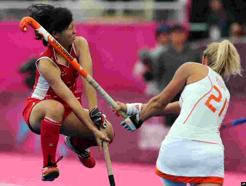Japan's Shiho Otsuka jumps to avoid being hit by Netherlands Sophie Polkamp during their women's field hockey preliminary round match.