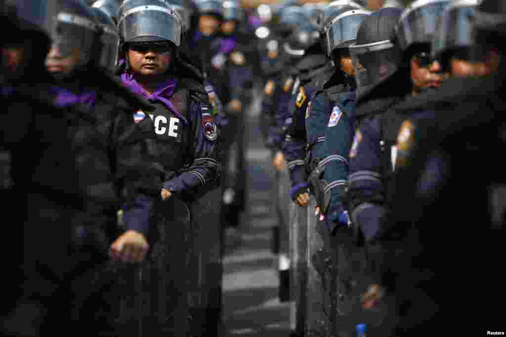 Police wear their riot gear inside Government House, as anti-government protesters gather behind its fence and gates in Bangkok, Dec. 12, 2013.