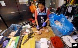 FILE - Restaurant owner A.J. Han chops prepares fresh chick at her Korean-style fried chicken shop, Stars in the Sky, in Edmonds, Washington, Dec. 12, 2017.