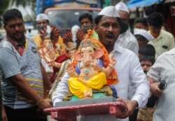 Para pria membawa patung dewa Hindu Ganesha ke rumah mereka, pada hari pertama festival "Ganesh Chaturthi" yang berlangsung selama sepuluh hari, di tengah wabah COVID-19, di Mumbai, India, 10 September 2021. (REUTERS/ Francis Mascarenhas)