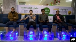 Palestinians soak their feet in tank stocked with fish at a cafe in Gaza City. The Gaza cafe operator said his business is booming after launching the fish pedicure service in the beleaguered Gaza Strip, Dec. 26, 2018. 