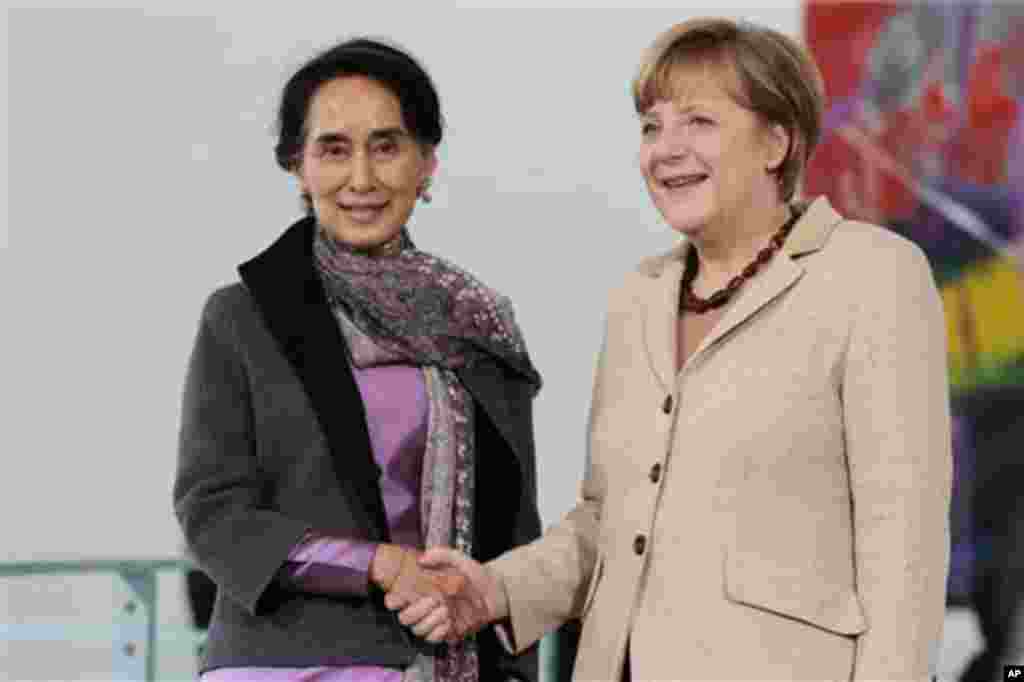 German Chancellor Angela Merkel, right, welcomes Myanmar Opposition Leader Aung San Suu Kyi, center, for a meeting at the chancellery in Berlin, Germany, Thursday, April 10, 2014. (AP Photo/Markus Schreiber)