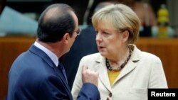 Germany's Chancellor Angela Merkel (R) and France's President Francois Hollande arrive for a working session during an EU summit in Brussels, Oct. 24, 2014. 