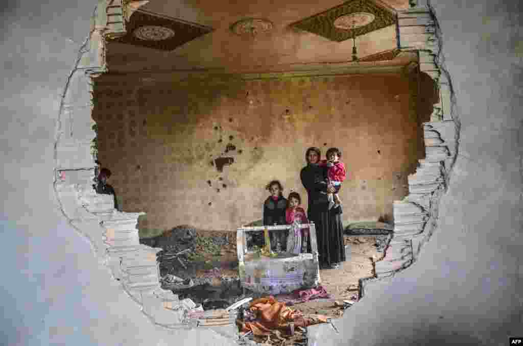터키 남동부 이라크 접경 마을 실로피의 부서진 주택 안에 여성과 아이들이 서있다. 터키 정부는 통행금지령을 내리고, 분리주의 쿠르드 반군을 소탕하기 위한 대대적인 공세를 시작했다.