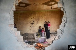 A women and her children stand in the ruins of battle-damaged house in the Kurdish town of Silopi, in southeastern Turkey, near the border with Iraq on January 19, 2016.