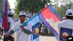 A supporter of the opposition Cambodia National Rescue Party holds the party flag together with a Cambodian national flag during an election campaign in Phnom Penh, Cambodia, June 27, 2013.