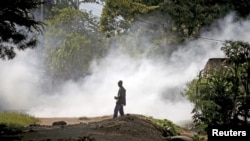 A protester watches after a policeman threw a teargas canister during a protest against Burundi President Pierre Nkurunziza and his bid for a third term in Bujumbura, Burundi, June 2, 2015.
