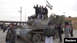 Free Syrian Army fighters pose on a tank after they said they fought and defeated government troops from the town of Ras al-Ain, near the province of Hasaka, 600 kilometers from Damascus, November 22, 2012.