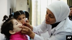 FILE - A health worker administers polio vaccine to a child as part of a UNICEF-supported vaccination campaign at the Abou Dhar Al Ghifari Primary Health Care Center in Damascus, Syria, Oct. 29, 2013.
