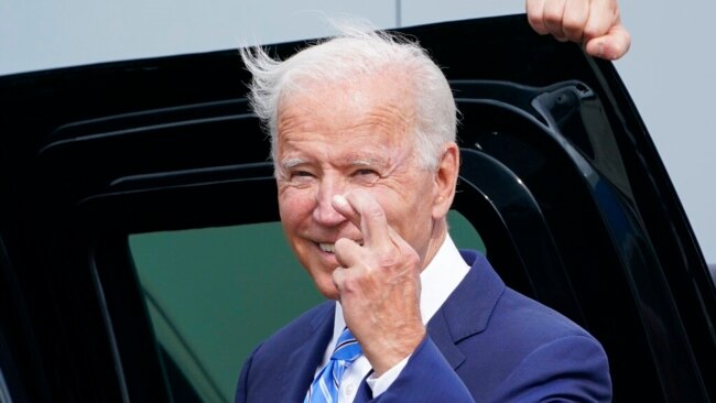 US President Joe Biden crosses his fingers as he responds to a question about the short-term debt deal as he arrives Air Force One at O'Hare International Airport in Chicago, Oct. 7, 2021.