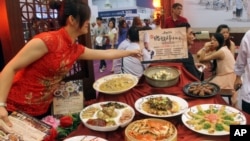 FILE - A saleswoman arranges a Taiwan's traditional food set designed to entertain guests during the Taiwan International Culinary Exhibition at the World Trade Center in Taipei, Taiwan.