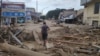 Seorang warga berjalan di antara batang-batang kayu yang terbawa air sungai yang meluap akibat banjir bandang di Luwu Utara, Sulawesi Selatan, 14 Juli 2020. (Foto: Tim SAR UNHAS Makassar)