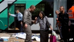 Un policía fronterizo israelí acompaña a una mujer en la escena del ataque palestino de este martes.