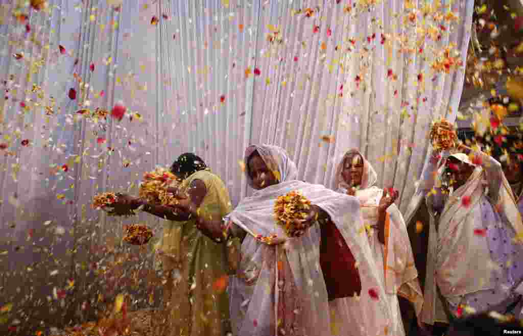 Para janda melempar bunga ke udara selama perayaan Holi atau festival warna di Vrindavan, negara bagian Uttar Pradesh (24/3). (Reuters/Vivek Prakash)