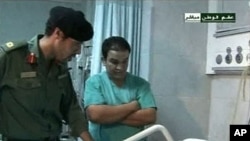 Still image from video footage by Libyan state television on August 9, 2011, shows what it says is Khamis Gadhafi (L) visiting wounded Libyans in a hospital