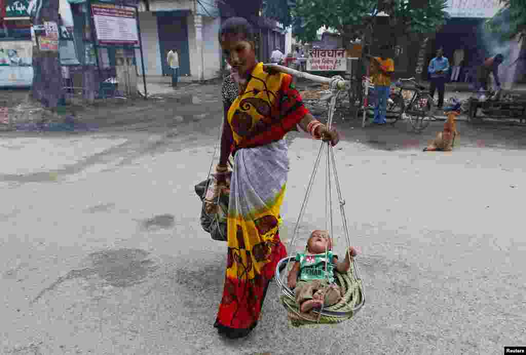 A woman carries her child in a basket in Allahabad, India.