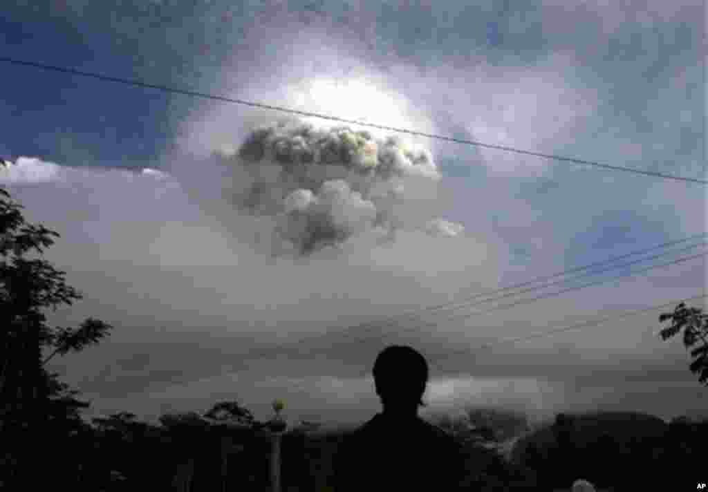 An Indonesian man watches as Mount Merapi erupts in Kepuharjo, Yogyakarta, Indonesia, Wednesday, Nov. 3, 2010. Indonesia's most dangerous volcano is once again sending searing gas clouds and burning rocks down its scorched flanks. (AP Photo/Gembong Nusant