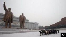 Warga Korea Utara memberi hormat kepada patung mendiang pemimpin Korea Utara, Kim Il-sung dan Kim Jong-il di Mansu Hill, saat salju menyelimuti Pyongyang, Korea Utara (21/12). Media setempat mengabarkan wisatawan Amerika, Bae Jun Ho ditahan di negara itu atas tuduhan melakukan tindak kejahatan.