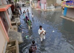 Warga berjalan kembali ke rumah mereka setelah mendapatkan paket bantuan pangan yang dibagikan oleh pasukan paramiliter di daerah yang terdampak banjir di Karachi, Pakistan, Rabu, 26 Agustus 2020.