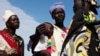 FILE - A woman carries a baby as she talks with other women talk at a food distribution center in Minkaman, Lakes State, South Sudan.