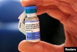 FILE - A nurse holds a vial of measles, mumps and rubella vaccine at Boston Children's Hospital in Boston, Feb. 26, 2015.