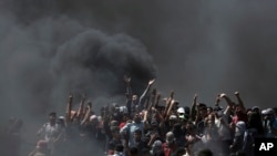 FILE- Palestinian protesters chant slogans as they burn tires during a protest on the Gaza Strip's border with Israel, May 14, 2018.