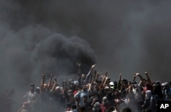 FILE- Palestinian protesters chant slogans as they burn tires during a protest on the Gaza Strip's border with Israel, May 14, 2018.