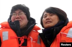 Family members of victims onboard the sunken ferry Sewol react as they look on during its salvage operations at the sea off Jindo, South Korea, March 26, 2017.