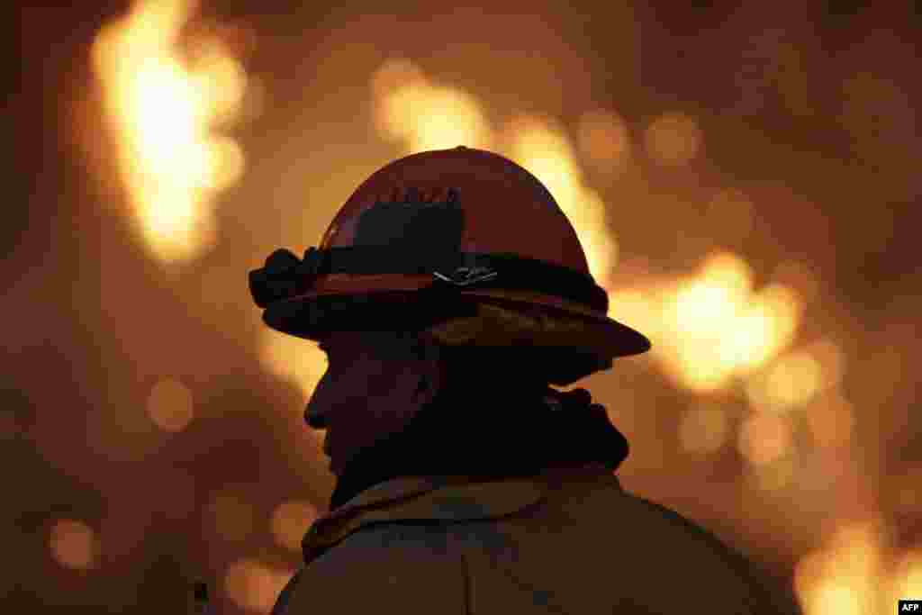 Một người lính chữa lửa theo dõi đám cháy Colby sang ngày thứ hai tại một sườn đồi bên trên xa lộ 39 ở Azura, bang California. Ba người đã bị bắt và bị truy tố về tội gây ra đám cháy hiện đã thiêu hủy 1.700 hecta rừng và một số nhà tại Thung lũng San Gabriel.