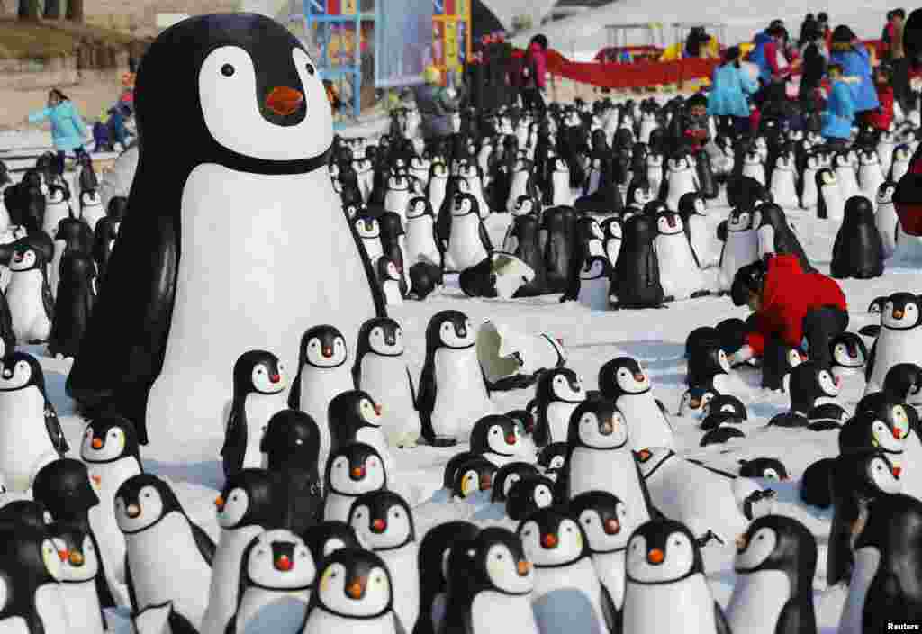 A girl plays with snow inside a display of plastic penguins during the Ice and Snow carnival at Taoranting park in Beijing, China.
