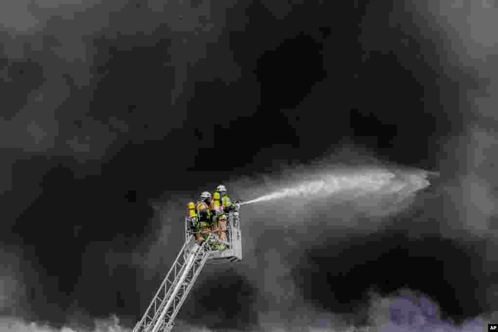 Fire fighters extinguish a fire at a burning storage hall at the Dong Xuan Center, a huge Asia market, in Berlin, Germany.