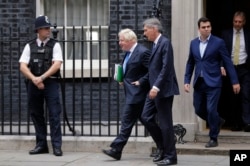Britain Chancellor of the Exchequer Philip Hammond, center, departs with the Foreign Secretary Boris Johnson after a Cabinet meeting at 10 Downing Street in London, Sept. 21, 2017.