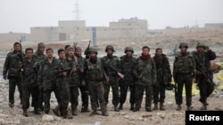 Syrian army soldiers loyal to Syria's President Bashar al-Assad pose for a photograph with their weapons in the Aleppo town of Naqaren, after claiming to have regained control of the town, Jan. 13, 2014.
