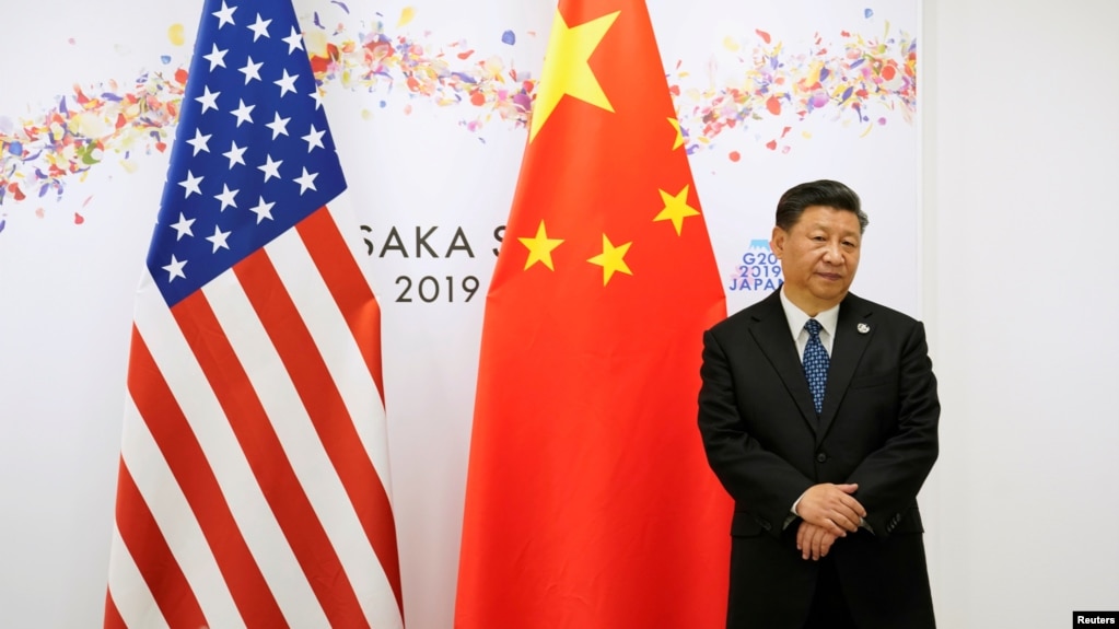 资料照:中国国家主席习近平在日本出席G20峰会期间在美中国旗前等候美国总统特朗普前去参加双边会谈。(2019年6月29日))