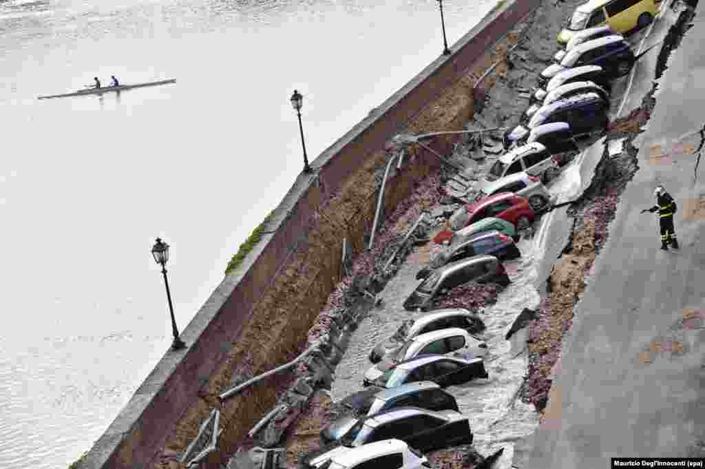 A firefighter stands next to vehicles stuck in a chasm near Ponte Vecchio, Florence, Italy. A chasm measuring about 200 meters long and seven meters wide opened up in central Florence due to the rupture of a main water pipe, according to media reports.